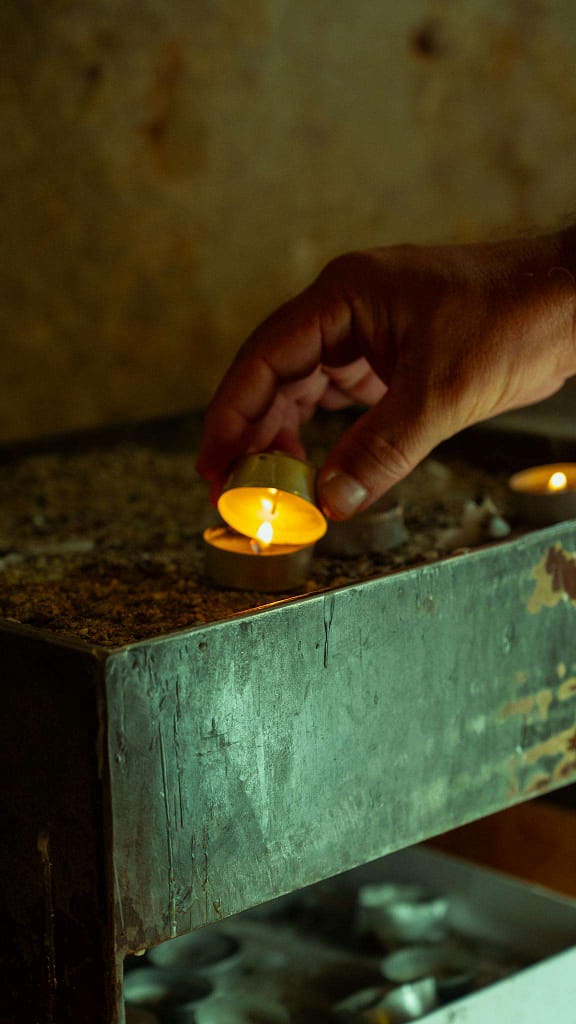 Ryan Polly Interspiritual Guide & Ritualist | Ryan Polly A hand placing a votive candle on a stand, creating a serene atmosphere.